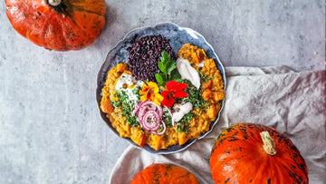 Kürbis-Linsen-Curry serviert auf einem schönen Teller mit schwarzem Reis und roten Zwiebeln