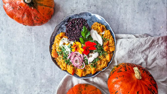 Kürbis-Linsen-Curry serviert auf einem schönen Teller mit schwarzem Reis und roten Zwiebeln