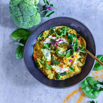 Cremiges veganes Brokkoli-Curry mit Gemüse, Spinat und Kräutern in schwarzer Schüssel angerichtet.