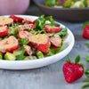 Frischer veganer Erdbeer-Salat mit grünem Salat und cremigem Dressing auf hellem Teller angerichtet.