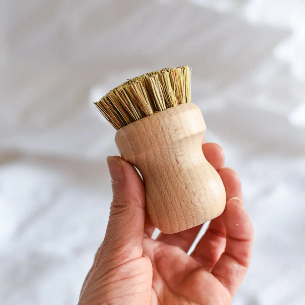 Kompakte Holzbürste mit Naturborsten wird in der Hand gehalten – ideal zum Reinigen von Pfannen, Töpfen und Geschirr in der Küche.