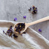 Holzlöffel mit getrockneten Blüten und Kräutern auf Stoff – ideal zum Servieren und für natürliche Küche.