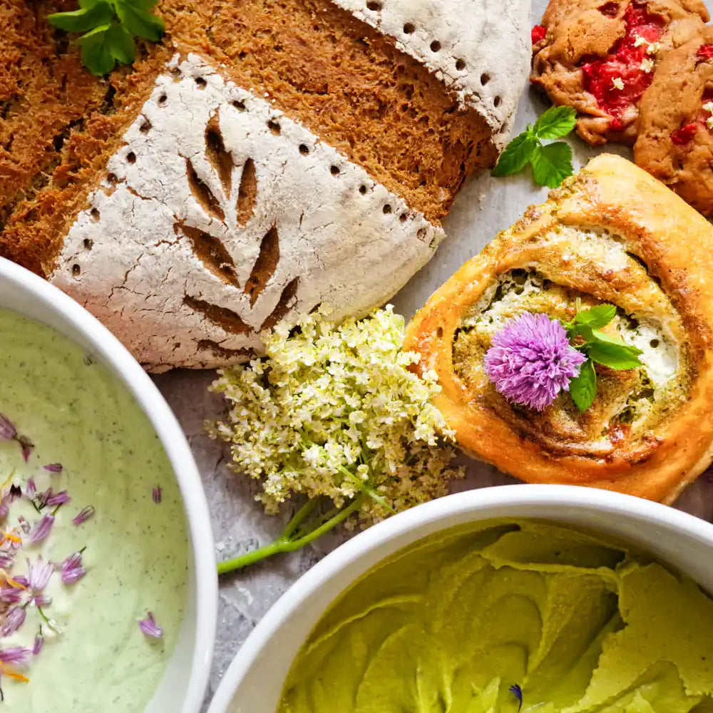Kräuterjause mit Wildkräuteraufstrichen, frischem Brot, Blüten und veganen Aufstrichen aus der Naturküche