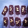 Vegane Eisriegel mit dunkler Schokolade, Erdnüssen und cremiger Erdnuss-Karamell-Füllung auf Backpapier.