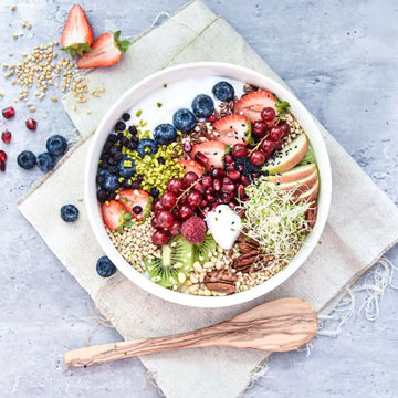 Vegane Frühstücksbowl mit Beeren, Kiwi, Nüssen, Sprossen und Samen – voller Farben und Vitamine.