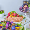 Gefüllte Süßkartoffel mit würziger Linsenfüllung, Rotkrautsalat, frischen Kräutern und essbaren Blüten als gesundes Sommergericht.
