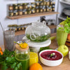 Vielfältige Auswahl an gesunden Getränken und Speisen mit Wildkräutern, grünem Smoothie, Kräutertee, Chia-Drink, Fruchtsaft und roter Gemüsesuppe. Frische Äpfel, Orangen und Kräuter auf einem Holztisch in einer natürlichen Küche für ganzheitliche Ernährung und Detox.