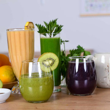 Verschiedene Smoothies und Säfte mit Wildkräutern, Kiwi, Beeren und Zitrusfrüchten für natürliche Gesundheit.