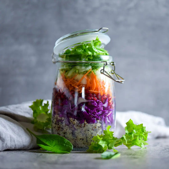 Farbenfroher Schichtsalat im Bügelglas mit Quinoa, Rotkohl, Karotten, Granatapfel und frischem grünen Salat.