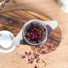 Getrocknete Rosenblüten in einem Teesieb zur Zubereitung von aromatischem Rosentee.