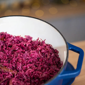 Gekochtes Rotkraut in einem blauen Topf, Nahaufnahme des Inneren, im Hintergrund warmes unscharfes Licht.